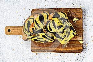 Unusual pumpkin marbled tiger print bread with cuttlefish ink, braided on a wooden board on a light background.