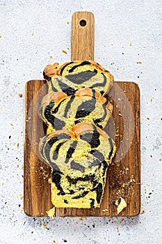 Unusual pumpkin marbled tiger print bread with cuttlefish ink, braided on a wooden board on a light background.