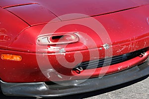 Unusual turn signal light on red sports car with damage to fender.