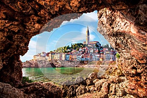 Unusual view with old clock towe in Piran through a rock hole. the tourist center of Slovenia. popular tourist attraction.