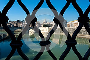 Unusual view from Ponte San Angelo of the basilica of San Pietro and the Tiber river behind the grates