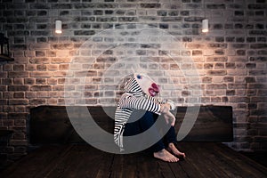 Unusual young man in comical mask sits alone on the bed