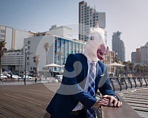 Unusual young man in elegant suit stands on the city waterfront