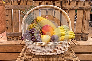 Unvarnished wicker basket filled with fresh fruits, bananas, mango, plums