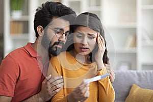 Unwanted Pregnancy. Worried young indian couple looking at positive test