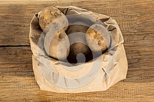 Unwashed potatoes in a paper bag islated on white