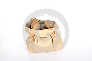 Unwashed potatoes in a paper bag islated on white