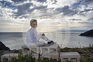 Unwavering Confidence: A Handsome Boy Poses on the Cliff at Sunset