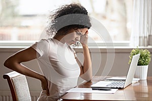 African American woman suffer from backache working at table photo