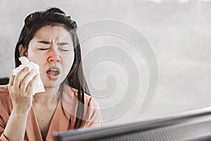 Unwell female Asian having flu and cold sneezing at work place