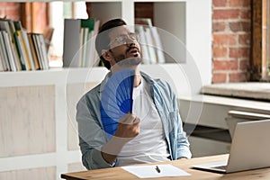 Unwell male employee wave with hand fan