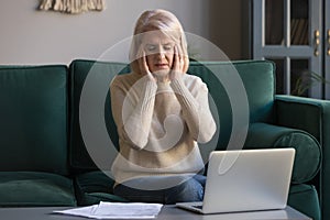 Unwell mature woman suffer from headache overworked on laptop