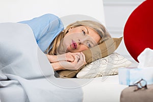 unwell woman laying on couch at home