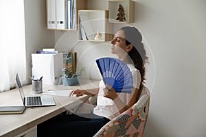 Unwell woman wave with waver suffering from heatstroke photo