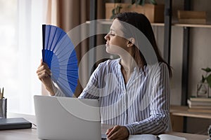 Unwell woman work at computer wave with hand fan