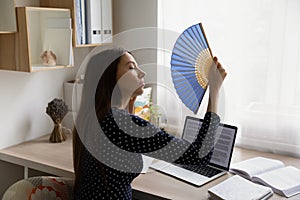 Unwell woman work at desk wave with hand fan
