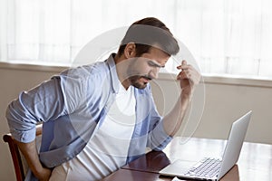 Unwell young man suffer from working in incorrect posture