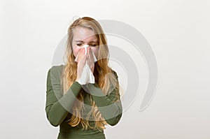 Unwell young woman blowing her nose