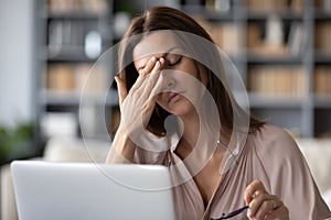 Unwell young woman take off glasses suffering from headache photo