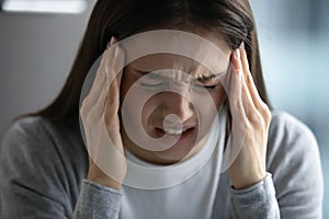 Unwell young woman suffer from migraine at workplace