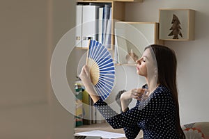 Unwell young woman wave with hand fan at home