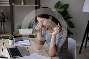 Unwell young woman work on laptop suffer from dizziness photo