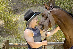 An unwilling horse turns away from the camera as the cowboy laughs.