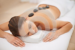 Unwinding with a hot stone massage. a gorgeous young woman enjoying a hot stone massage.