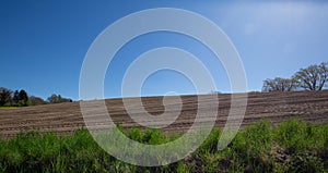 Unworked field with green grass in the front