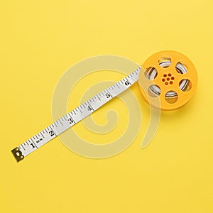 Unwound measuring tape on a yellow coil on a yellow background. Flat lay