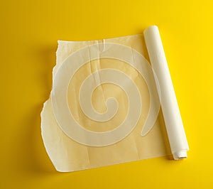 unwound white parchment baking paper on a yellow background