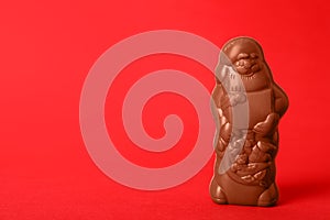 Unwrapped chocolate Santa Claus on red background. Space for text