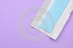 Unwrapped stick of chewing gum on violet background, top view. Space for text