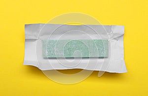Unwrapped stick of chewing gum on yellow background, top view