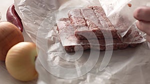 Unwrapping Raw Cevapcici Sausages on Table.