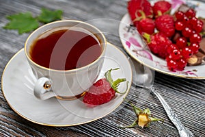 Ñup of tea and fresh raspberries on a wooden table close-up