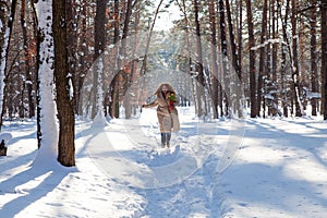 Upbeat charming woman in warm coat walking through snowy forest