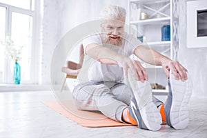 Upbeat elderly man stretching and touching his toes