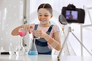 Upbeat girl pouring chemicals and recording vlog