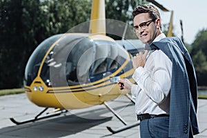 Upbeat man posing with credit card while standing at helipad