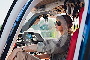 Upbeat mood. Beautiful helicopter pilot smiling cheerfully while listening to air traffic controller in her headphones.