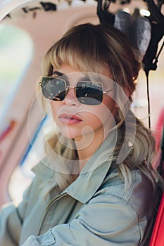 Upbeat mood. Beautiful helicopter pilot smiling cheerfully while listening to air traffic controller in her headphones.