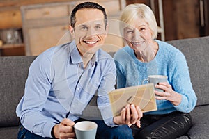 Upbeat mother and son posing while looking at old photo