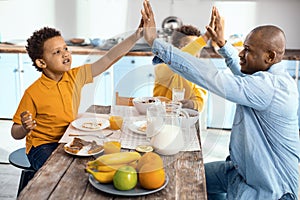 Upbeat single-parent family high-fiving each other at breakfast