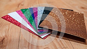 Upclose photo of a pile of colorful rectangular paper tiles covered with sparkling glitter