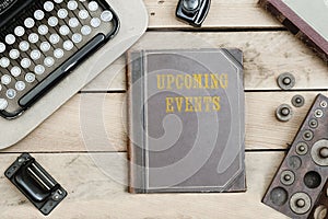 Upcoming Events on old book cover at office desk with vintage it