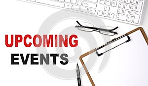 UPCOMING EVENTS text written on the white background with keyboard, paper sheet and pen