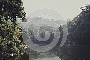 Upcountry of China with man stroke boat in mountain forest view photo