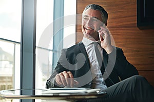 Updating his client over the phone. a businessman answering a phonecall while sitting in his office.