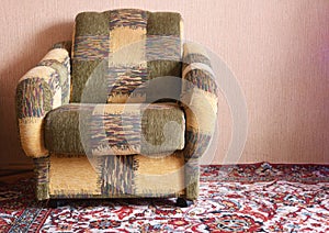 Upholstered furniture armchair and carpet on the floor in a Soviet apartment, interior in the style of the 90s. Old design in the